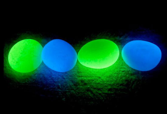 Quatre galets phosphorescents — émeraude et saphir — luisant dans l'obscurité